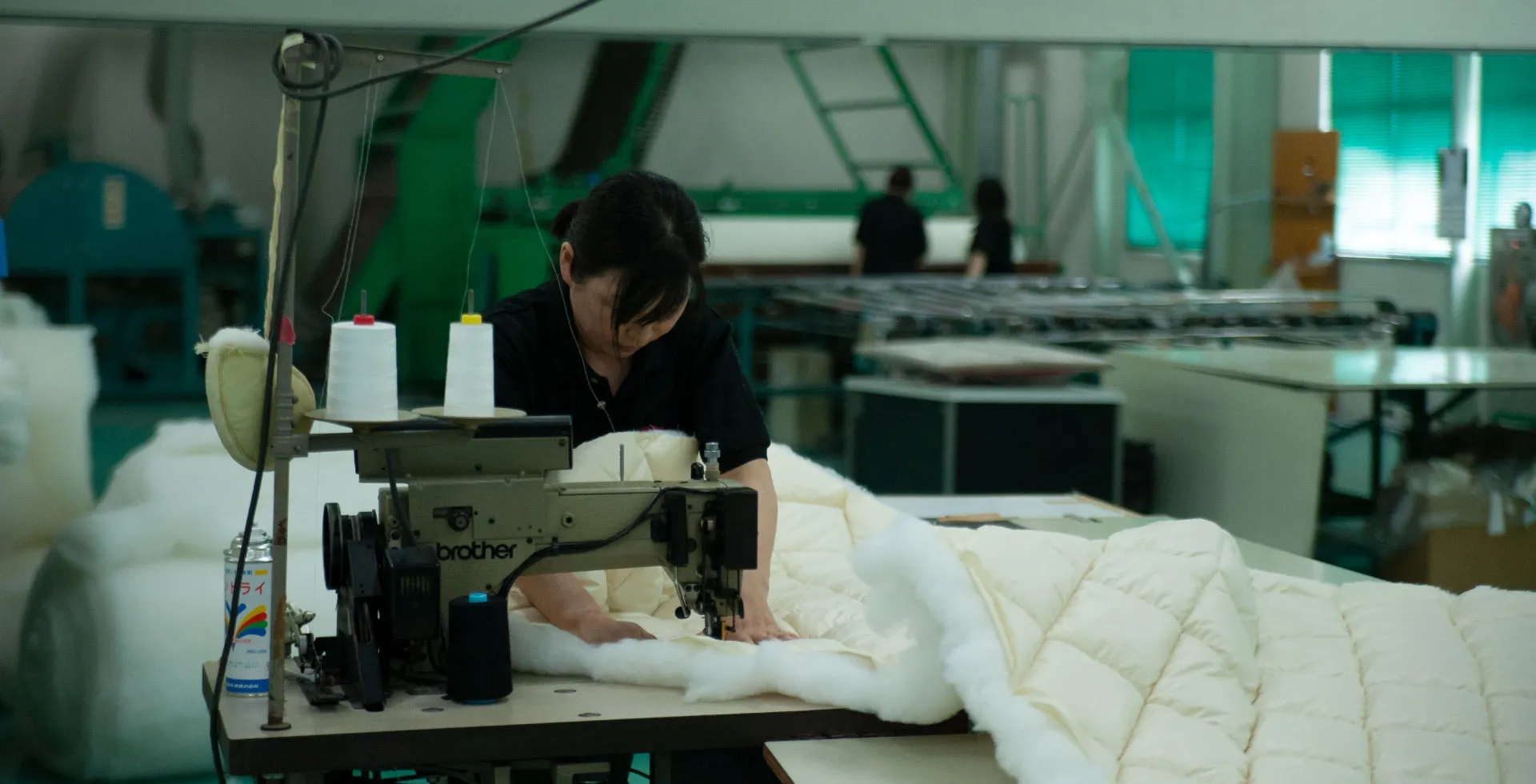 An OFUTON KOBO craftsperson sewing a shikibuton in the workshop